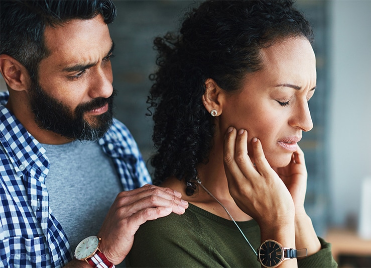 Image depicting a woman with jaw pain and a man comforting her, highlighting TMJ treatment services at The Cosmetic Dentists of Austin.